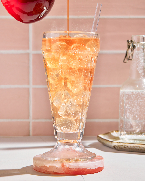 Deux verres de julep à la menthe sans alcool avec de la glace pilée et garnis de menthe, présentés avec un bol de feuilles de menthe, une carafe de julep préparé et une carafe de sirop simple à la menthe.