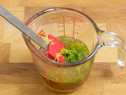Une tasse à mesurer en verre avec jus et zeste de lime, et une spatule