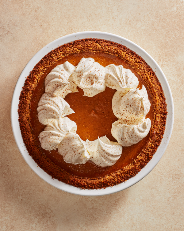 Tarte à la citrouille entier avec crème fouettée et cannelle moulue dans un plat à tarte blanc