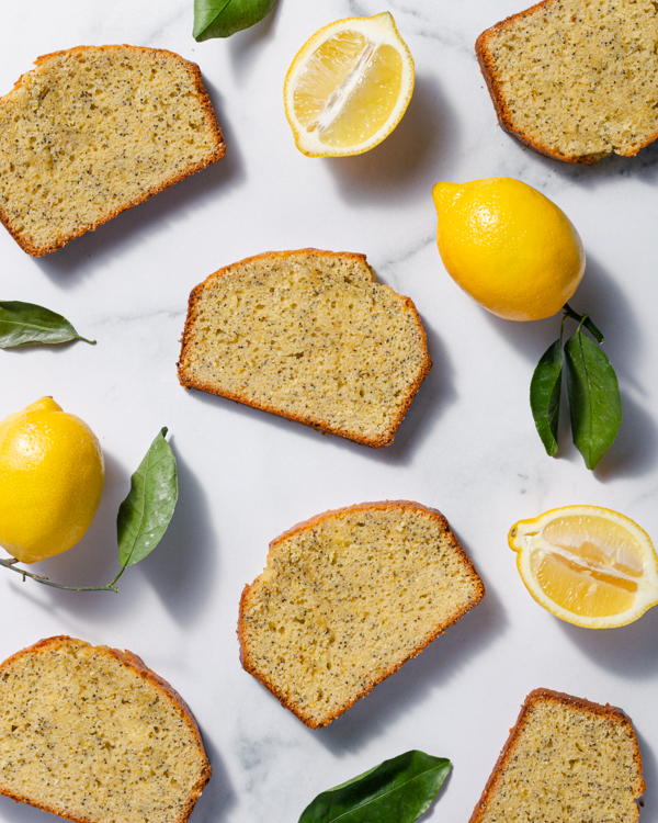 Tranches de gâteau quatre-quarts sur un comptoir marbré avec des feuilles vertes et citrons