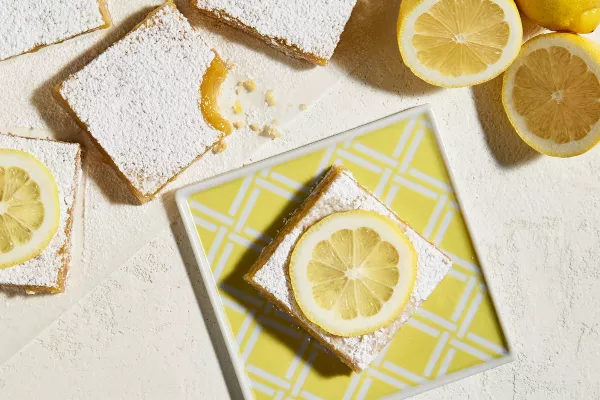 Barres de citron sur une assiette carré jaune avec des tranches de citron