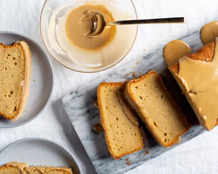 Tranches de gâteau à la bière couvert de glaçage sur une plaque de marbre, avec un bol de glaçage et deux assiettes garnies de t