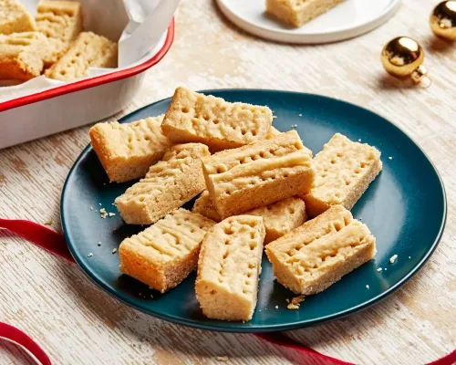 Des sablés sur une assiette bleue avec des rubans rouges et des ornements dorés de Noël