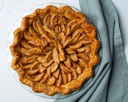 Une tarte hollandaise aux pommes sur une assiette avec un linge de cuisine