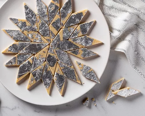 kaju katli sur une assiete coupé en losanges et décoré de feuilles d'argent
