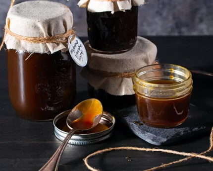 Quatre pots de sirop à la mélasse pour pancakes, dont un ouvert avec une cuillère à côté