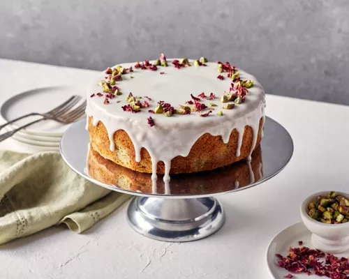 Un gâteau d’amour persan glacé et décoré de pétales de roses sur un support argenté