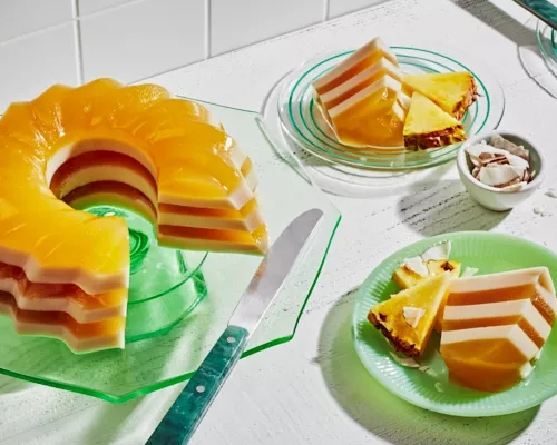 Gelée anglaise au piña colada sur un verre vert, avec deux tranches coupées et servies dans des assiettes vertes dépareillées.
