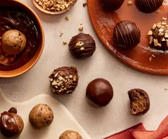 Des bouchées de pâte à biscuits trempées dans le chocolat à différents stades de préparation, certaines saupoudrées de noix, une avec une bouchée en moins.