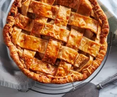 Tarte aux pommes garnie de treillis sur une grille de refroidissement avec une pelle à tarte.