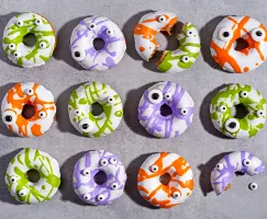 Beignes à la cannelle avec un glaçage coloré et des yeux en bonbons