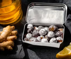 Pastilles contre la toux maison dans une boîte métallique, tranches de citron, gingembre et miel