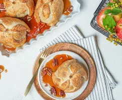 Trois baluchons aux pommes sur un plateau avec du sirop de pomme, et un autre sur une assiette