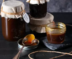 Quatre pots de sirop à la mélasse pour pancakes, dont un ouvert avec une cuillère à côté