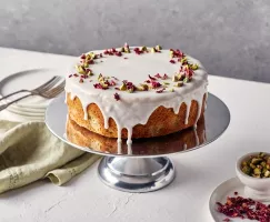 Un gâteau d’amour persan glacé et décoré de pétales de roses sur un support argenté