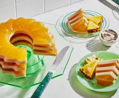 Gelée anglaise au piña colada sur un verre vert, avec deux tranches coupées et servies dans des assiettes vertes dépareillées.