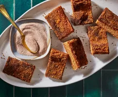 Sept barres de biscuits snickerdoodle sur un plateau blanc avec un plat de sucre à la cannelle et une cuillère dorée