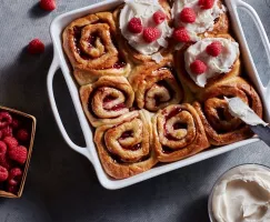 Petits pains frais végétaliens à la cannelle  et aux framboises dans un plat à four, certains sans glaçage, d'autres avec un gla
